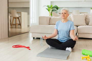 Yoga mindfulness meditation. Senior adult mature woman practicing yoga at home. Mid age old lady...