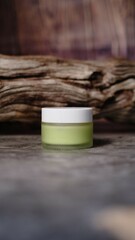 small glass jar with white cap containing light green liquid substance rests against piece of weathered wood adding natural element creating balanced aesthetic to the composition. 