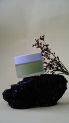small glass jar with white cap containing light green liquid substance rests against piece of weathered wood adding natural element creating balanced aesthetic to the composition. 