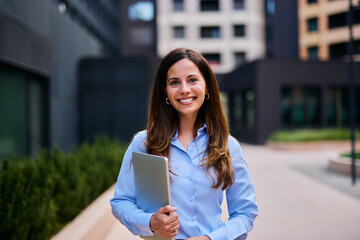 Confident Professional Woman Standing Outdoors With a Laptop