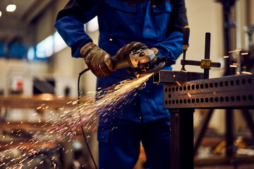 Worker Using an Angle Grinder on Metal, Producing Sparks in Industrial Workshop