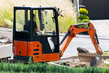A mini excavator removes debris during landscaping