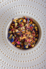 Herbal tea. Various dried herbs and fruits in a white plate on a light background. Tea ceremony. Healthy herbal drink.