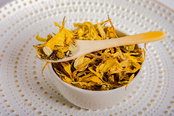Soothing or anti-inflammatory herbal tea. A mixture of dried yellow leaves and flowers in a plate...
