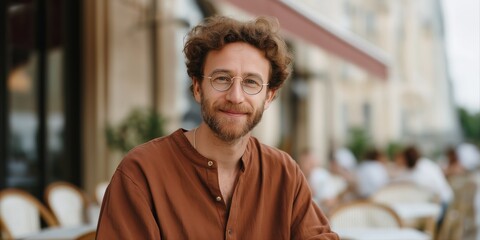 Smiling caucasian male adult with glasses at outdoor café in casual attire