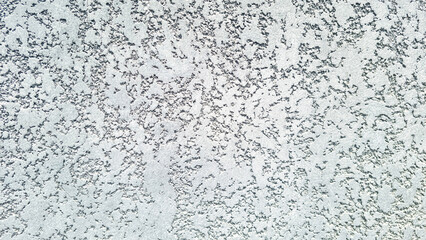 Close-up light grey stucco wall background texture with rough plaster. Architectural surface with...