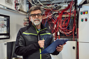 Engineer Conducting Inspection in a Server Room with Cables and Control Panels