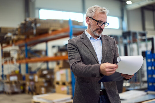 Business Professional Reviewing Documents in a Modern Warehouse Setting