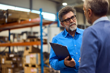 Two Businessmen Discuss Operations Inside a Warehouse Environment