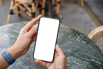 Mockup woman's hand holding using smart phone with white blank screen POV at coffee shop, mobile app design and advertising, online marketing
