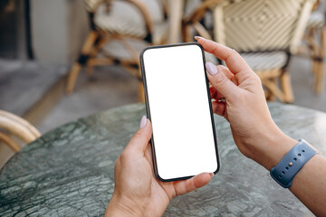 Mockup woman's hand holding using smart phone with white blank screen POV at coffee shop, mobile app design and advertising, online marketing