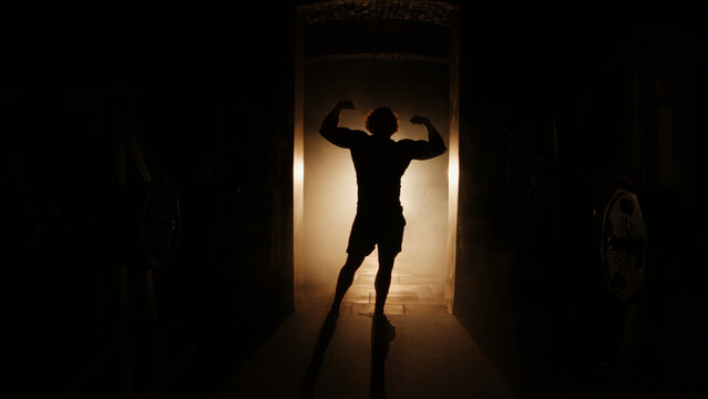 silhouette of a athletes posing, bodybuilder in a dark room