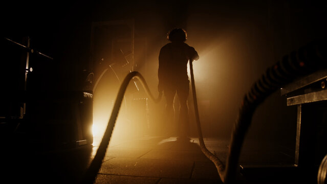 silhouette of a person working out in a gym with ropes, CrossFit exercise, cinematic shot