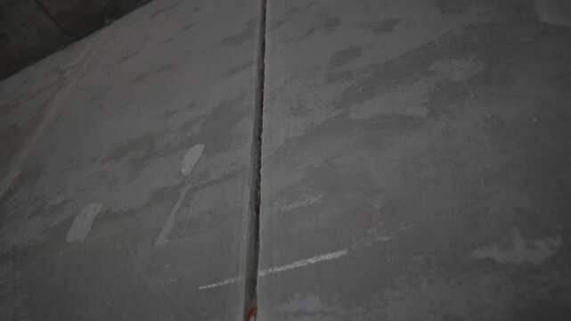 Unplastered seam runs across cold concrete slab. Uneven surface waits smoothing before finishing stage. Closeup shapes rigid materials