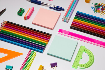Brightly colored stationery supplies including pencils, sticky notes, rulers, and clips are organized on a workspace, ideal for school projects or office tasks