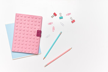 Brightly colored stationery is arranged on a smooth white surface. Two pencils, paper clips, and a notepad create an inviting workspace ready for creativity and organization
