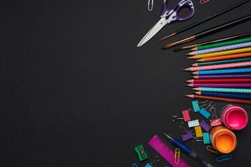 collection of crafting tools and supplies is thoughtfully arranged on a black background. Items include colored pencils, brushes, scissors, and paper clips, perfect for creative activities