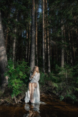 calm moment unfolds as a person in a flowing white dress sits gracefully by a quiet stream...