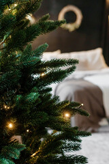 Bedroom interior decorated for Christmas holidays. Home interior with a Christmas tree on a dark wall background.
