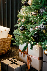 Designer Christmas tree decoration with lights. The concept of celebrating New Year and Christmas. Gifts in craft packaging under the Christmas tree.