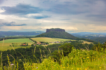 Scenic view over Saxon Switzerland with the distinctive Pfaffenstein rock formation and green rural landscape near Königstein, Germany, on a cloudy summer day