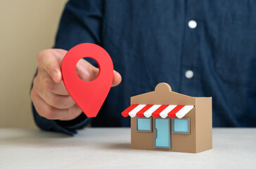 A man holds a geolocation pin near a store. Convenient location and high customer traffic. Business...
