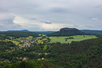 Scenic view over Saxon Switzerland with the distinctive Pfaffenstein rock formation and green rural landscape near Königstein, Germany, on a cloudy summer day