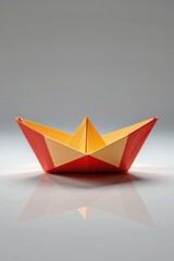 Fototapeta premium Colorful Origami Paper Boat on Smooth Surface with Reflection in Studio Lighting