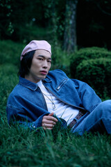 Stylish young man in denim lounging in a vibrant park setting during daylight