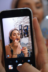 Taking a photo on a smartphone of a young beautiful woman applying lipstick. Everyday life. Concept of a woman's routine. beauty. self-care, blogging