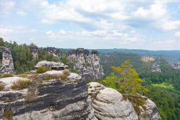 Bastei, Germany - June 3rd, 2025: Tourists walk along the historic Bastei Bridge in Saxon Switzerland National Park, Germany, surrounded by dramatic sandstone rocks and lush greenery on summer day