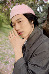 Fototapeta premium Young asian man showcases fashion in stylish grey outfit at serene park setting
