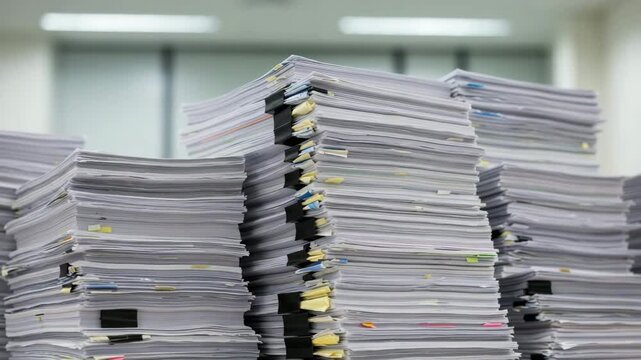 Stacked paperwork and documents in a cluttered office space  