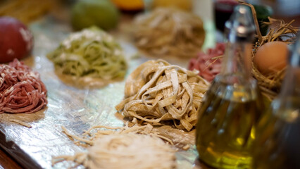 Assorted colorful raw pasta laid on a dusted surface, featuring various shapes and colors
