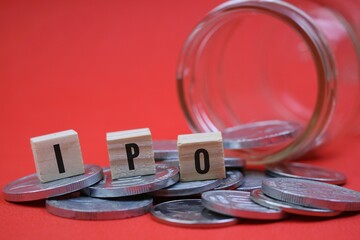 stock market and investment concept. ipo writing on wooden block and stack of coins isolated on red...