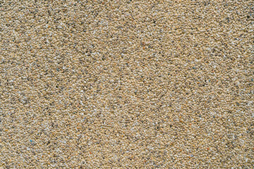 Textured surface of light brown gravel with fine grains and small stones suitable for background or abstract art projects