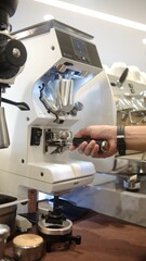 person barista using modern grinder machine to prepare coffee grounds in cafe features digital...