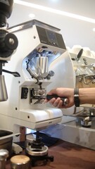 person barista using modern grinder machine to prepare coffee grounds in cafe features digital...