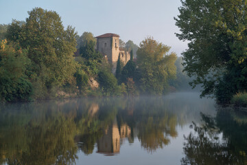 Fototapeta premium Historic Castle by the Riverbank with Mirrored Reflection