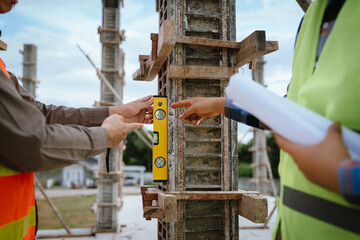 A construction worker inspects a concrete pillar using a level, ensuring precision and quality...