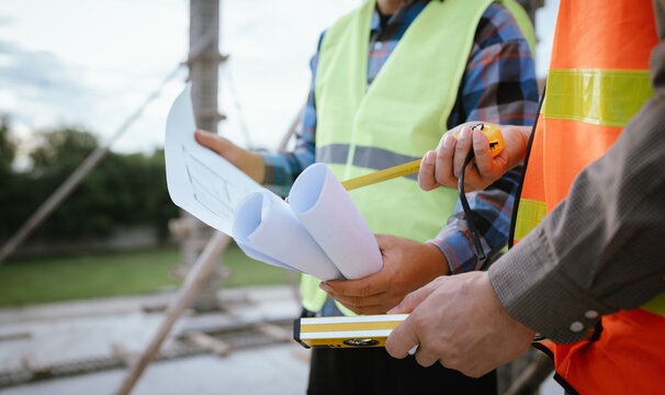 A construction worker inspects a concrete pillar using a level, ensuring precision and quality control during structural development in an urban building project under professional supervision and pla - Powered by Adobe