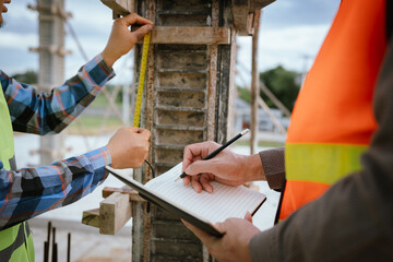 A construction worker inspects a concrete pillar using a level, ensuring precision and quality...