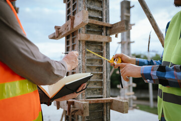 A construction worker inspects a concrete pillar using a level, ensuring precision and quality...
