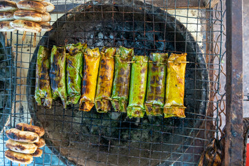 Traditional Grilled Banana Leaf Parcels on Charcoal Stove in Southeast Asia
