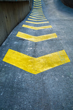 A row of yellow safety arrows painted on a road