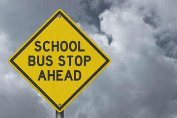 School Bus Stop Ahead yellow warning sign with sky