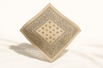 A beige bandana with a paisley pattern isolated on white background