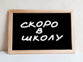 Fototapeta premium Chalk text on a board. Soon to school, text in Russian.
