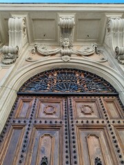 Detail of an ancient door in solid wood and with various metal decorations and sculptures in a period building in the center of Rome.