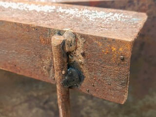Close-up of a heavily rusted metal beam with visible welds, showcasing the rugged texture and...